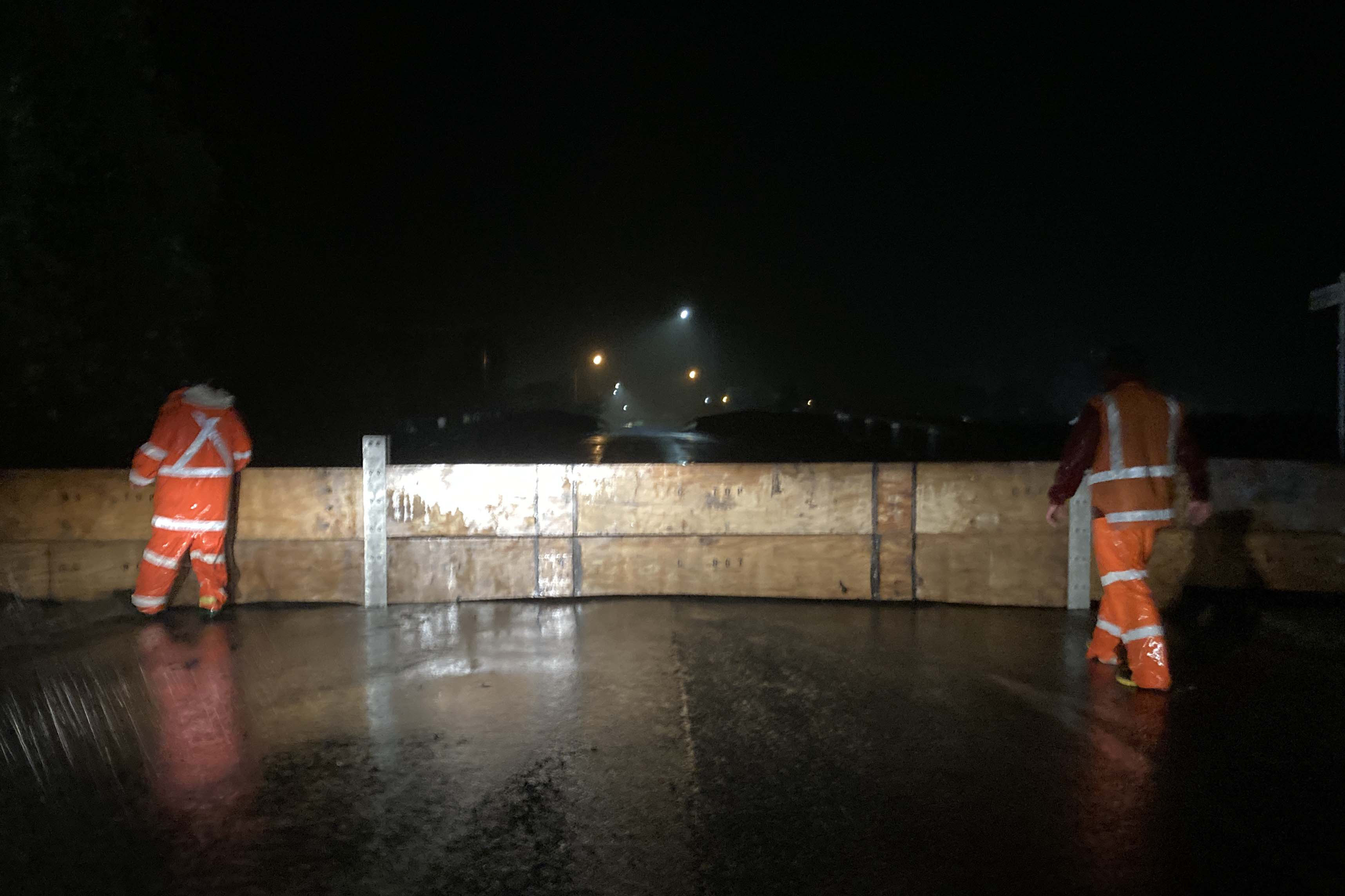 Operational staff erect stoplogs on the town side of the river during Cyclone Gabrielle.